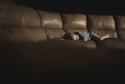 Boy sleeping on sofa in darkroom at home