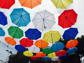 Low angle view of multi colored umbrellas hanging against sky
