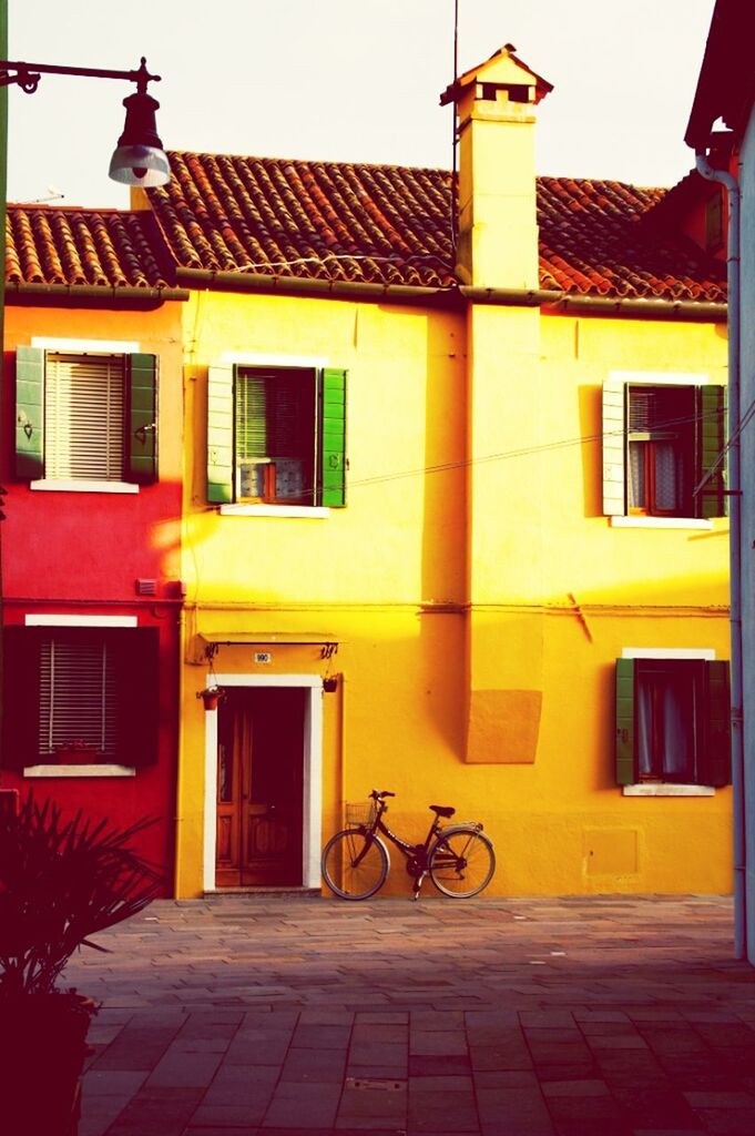 building exterior, architecture, built structure, bicycle, transportation, street, residential building, residential structure, mode of transport, cobblestone, house, land vehicle, city, building, street light, outdoors, yellow, parking, stationary, clear sky