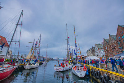 Sailboats moored in harbor against sky