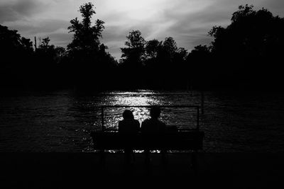 Silhouette of people in lake at sunset