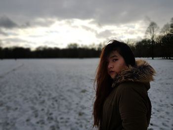 Side view portrait of young woman wearing warm clothing standing in snow
