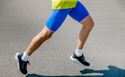 Legs male runner running on asphalt road