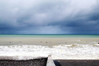 Scenic view of beach against cloudy sky