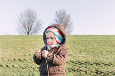 Portrait of man holding camera while standing on field