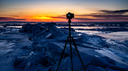 Snow covered land and sea against sky during sunset. baykal.