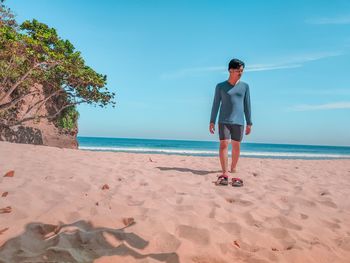 Full length of young man at beach against sky
