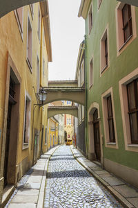 Alley amidst houses against sky