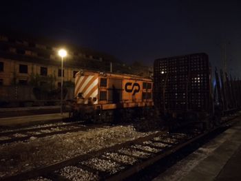 Train in illuminated city against sky at night