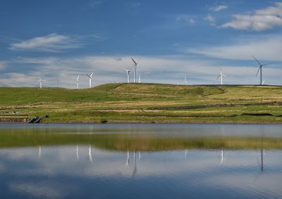 Scenic view of landscape against sky with wind turbines 