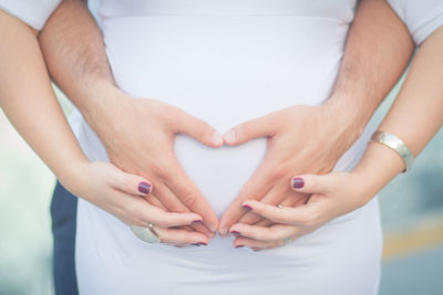 Man making heart shape on pregnant belly