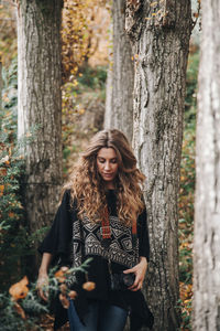 Beautiful female brunette with camera walking in forest