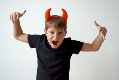 Portrait of smiling boy with arms raised standing against wall