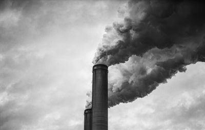 Low angle view of smoke emitting from chimney against sky