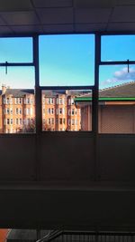 Buildings against sky seen through window