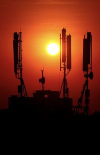 Silhouette of electricity pylon against sky during sunset