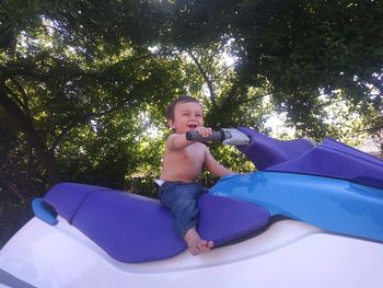 Low angle view of cute shirtless baby boy sitting on motorcycle