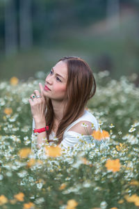 Side view of young woman with flower petals on field