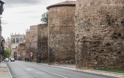 Road by buildings against sky