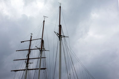 Low angle view of ship masts against cloudy sky