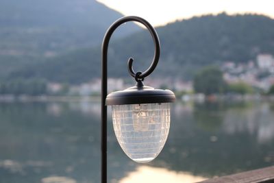 Close-up of glass against lake against sky