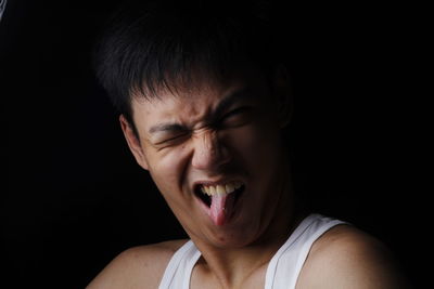 Young man teasing against black background