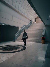 Rear view of man walking on staircase against building