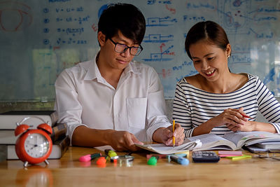 Friends studying with school supplies on table at home