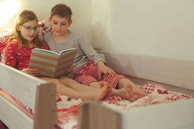 Cute sibling reading book at home