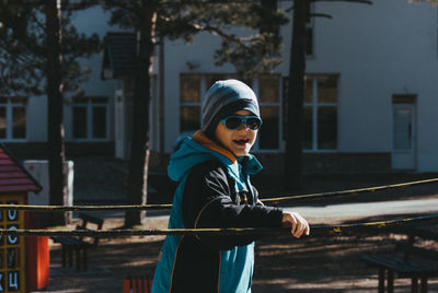 Portrait of cute smiling boy standing against house