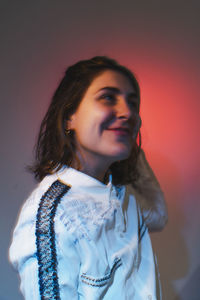 Portrait of young woman standing against wall