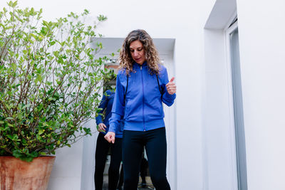 Woman standing by planter against wall