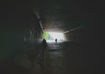 Rear view of man walking in tunnel