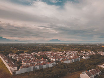 Aerial view of houses against cloudy sky