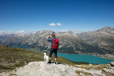 Woman with dog standing on mountain against sky