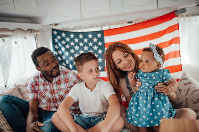 Cheerful family sitting against american flag