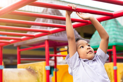 Boy hanging on parallel bars at park