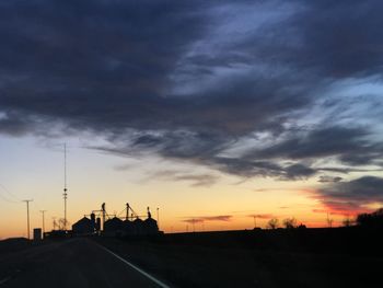 Silhouette of city against cloudy sky during sunset