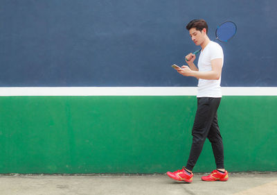 Side view of young man standing against wall