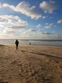 Woman walking on beach against sky