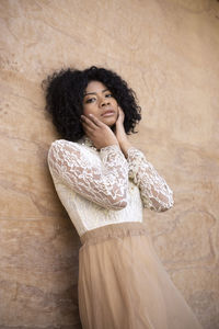 Portrait of young woman standing against wall