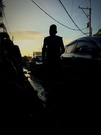 Rear view of silhouette man on car against sky