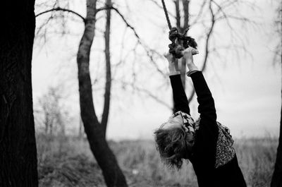 Woman holding rope against trees at forest