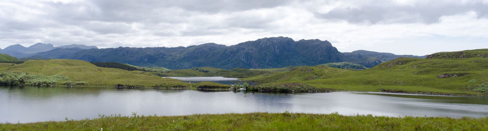 Scenic view of lake by mountains against sky