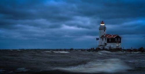 Lighthouse by sea against sky