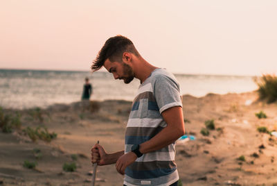 Young man standing on beach against sky