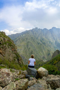 Rear view of woman looking at mountains against sky