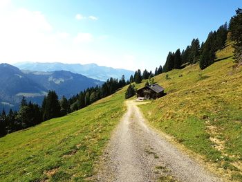 Road amidst green landscape and mountains against sky