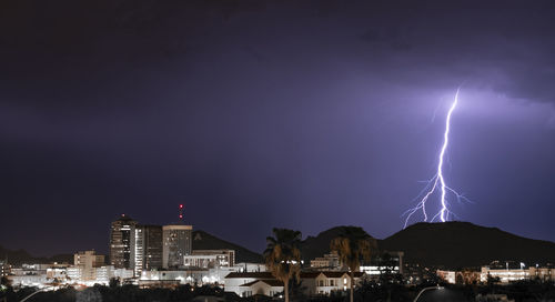 Lightning over illuminated buildings in city at night