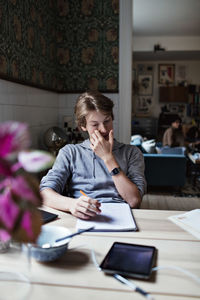 Teenage boy doing homework while sitting at table